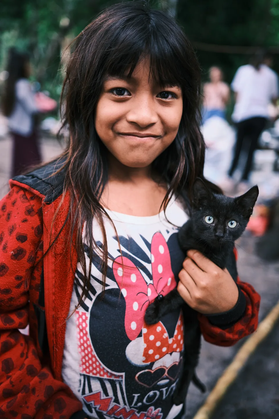 Criança indígena segura um gato no colo.