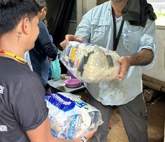 Voluntário entrega alimentos a um morador durante uma ação na comunidade.
