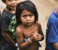 Criança da comunidade com outras crianças ao fundo.