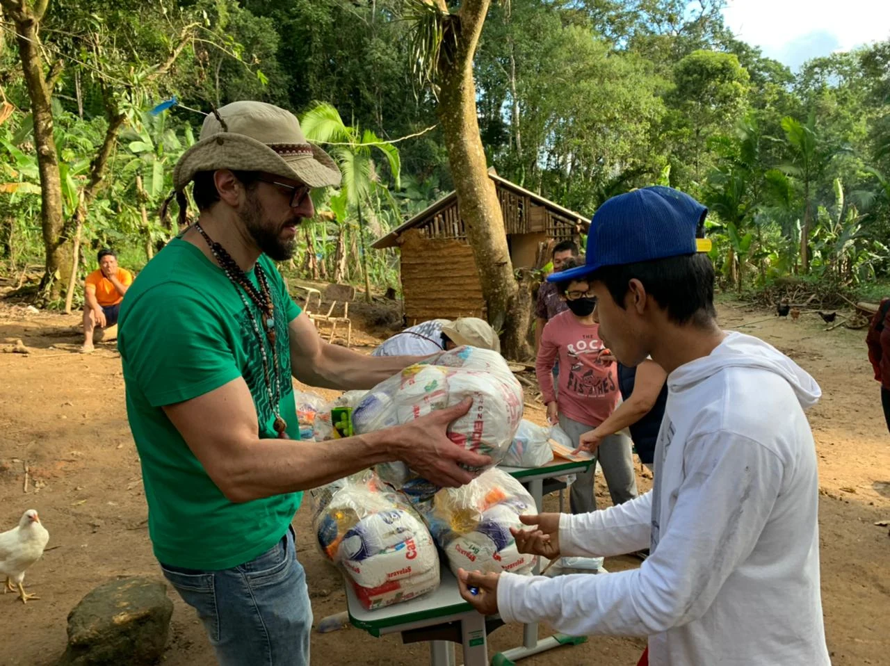 Voluntário entrega alimentos a um morador durante uma ação na aldeia.