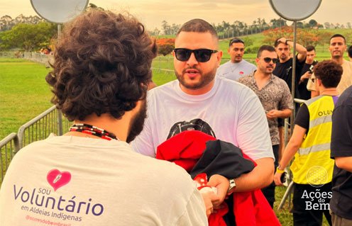 Voluntário do Ações do Bem, com camiseta "Sou Voluntário em Aldeias Indígenas", recebe doação de um participante do Circoloco